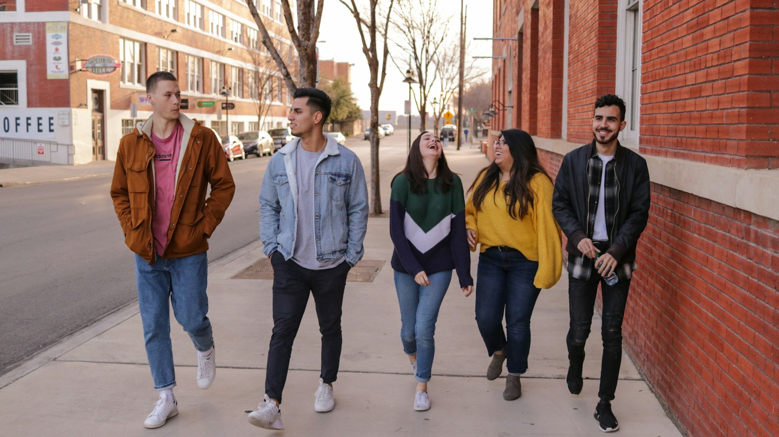 Five young people walking side by side and laughing